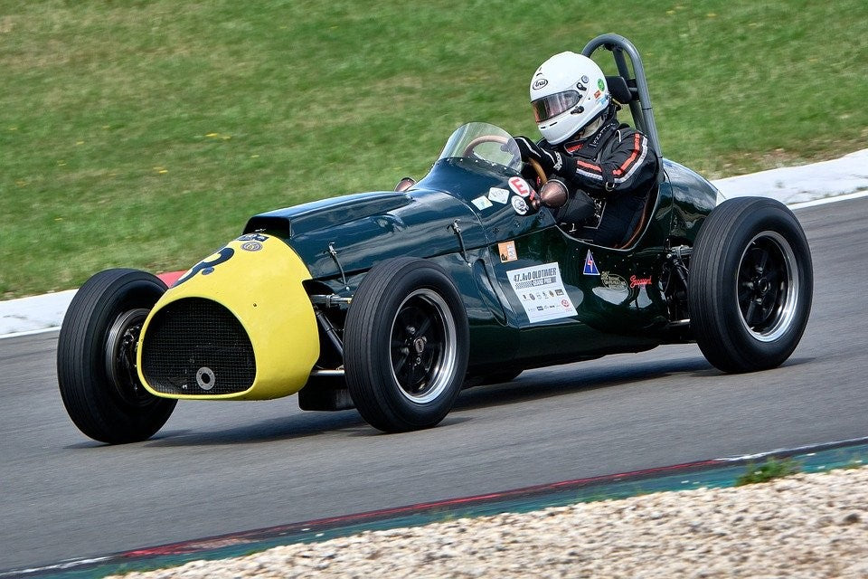 driver in racing suit driving a classic race car